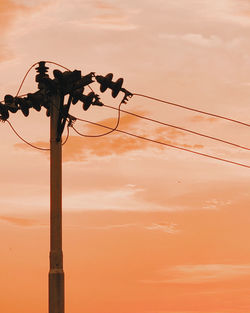 Low angle view of silhouette electricity pylon against sky during sunset