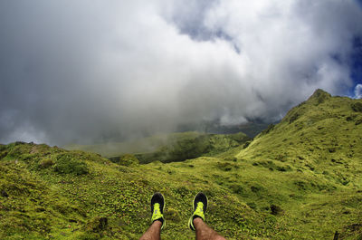 Low section of man on mountain against sky