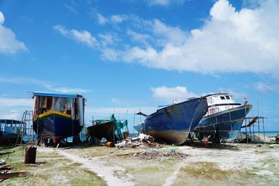 Abandoned boats moored on shore against sky