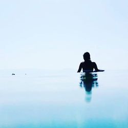 Silhouette man in swimming pool against clear sky