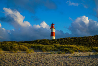 Red and white lighthouse by sea against sky on sylt