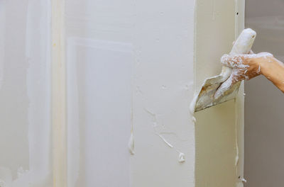 Close-up of hand against white wall