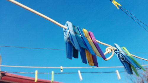 Low angle view of clothes drying on rope against blue sky