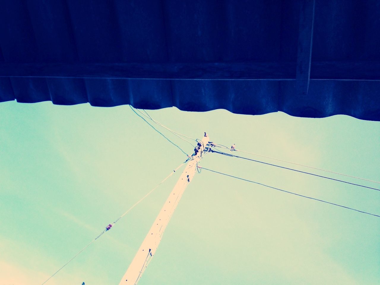 low angle view, power line, connection, cable, electricity, sky, power supply, fuel and power generation, technology, electricity pylon, blue, transportation, crane - construction machinery, day, outdoors, no people, development, silhouette, construction site, rope