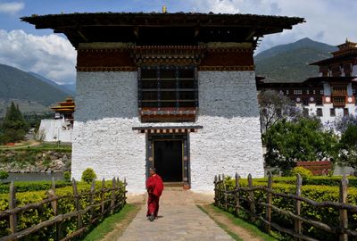 Rear view of a bhuddist monk walking into the temple structure.