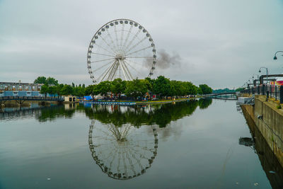 Ferris wheel by lake against sky