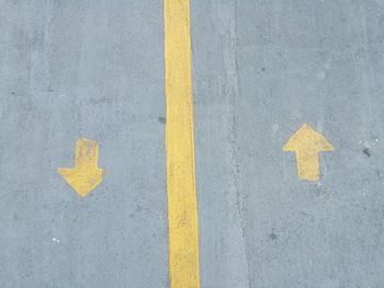 High angle view of yellow arrow symbol on road
