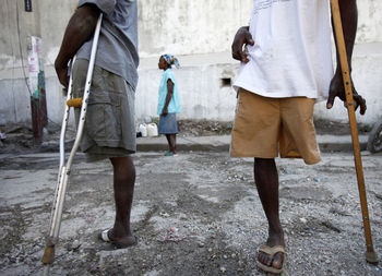 Low section of men with walking cane standing on footpath