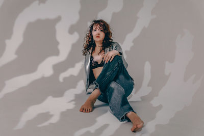 Portrait of young woman standing against wall