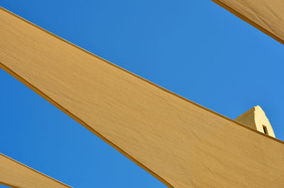 Low angle view of yellow fabrics hanging against clear blue sky