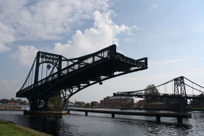 Low angle view of bridge over river against cloudy sky