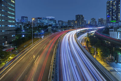 High angle view of light trails on road amidst buildings in city