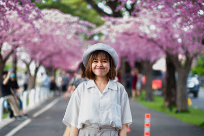 Portrait of beautiful young woman standing by cherry blossom
