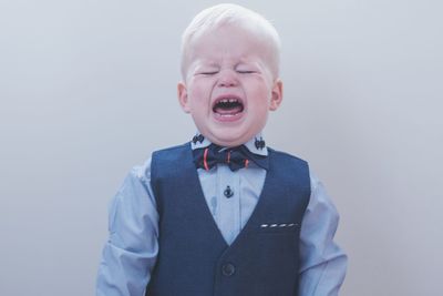 Cute boy crying against white background