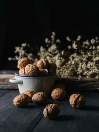 Roasted walnut in a ceramic bowl  with darker background and some dried flowers