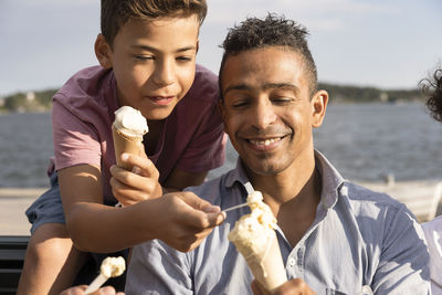 Happy father sharing ice cream with son during summer vacation