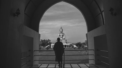 Rear view of woman standing by buildings against sky