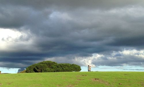 People standing on field against cloudy sky