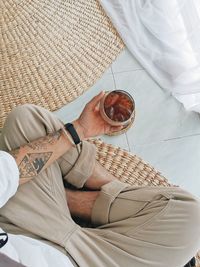 Midsection of man sitting with drink on floor