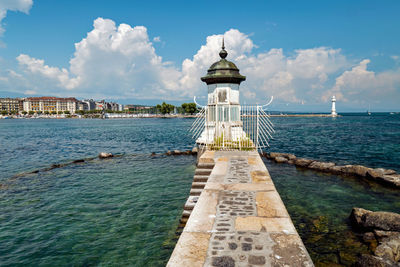 View of lighthouse by sea against sky