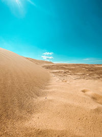 Sand dunes in desert against blue sky