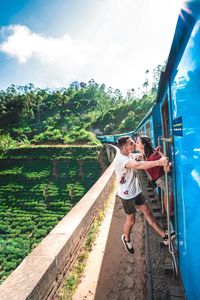 Young couple kissing while standing on passenger train doorway