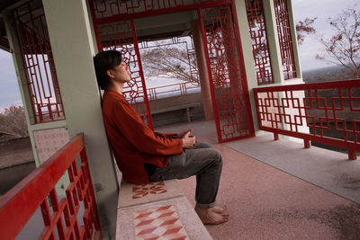 Side view of young man sitting on railing