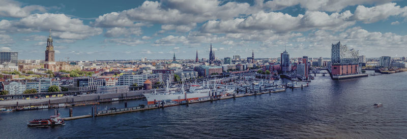 Panoramic view of buildings and river against cloudy sky