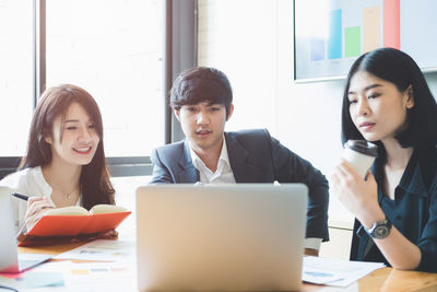 Colleagues discussing over laptop in office