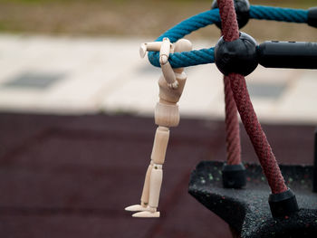 Close-up of wooden figurine hanging on rope