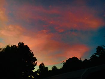 Low angle view of silhouette trees against dramatic sky