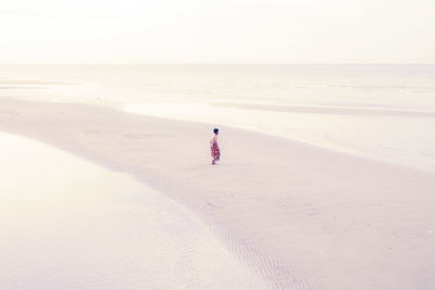 Full length of man walking on sandbar at beach against sky