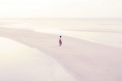 Rear view of woman on beach against sky