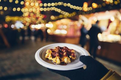 Cropped hand holding food in plate outdoors