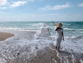 Woman standing on beach against sky