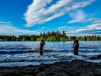 People on riverbank against sky