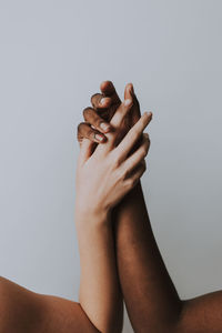 Cropped hands of women against gray background