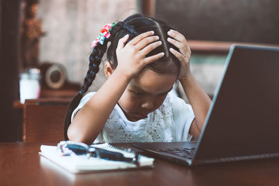 Midsection of girl using mobile phone while sitting on table