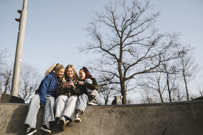 Teenage girls using phone in skatepark