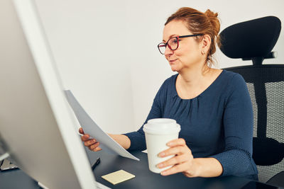 Woman entrepreneur working with satisfaction. business woman drinking coffee while working in office
