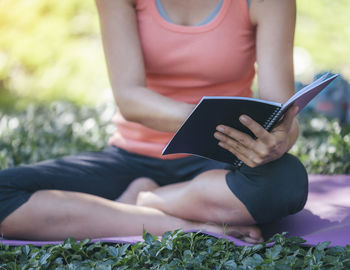 Midsection of woman using mobile phone while sitting outdoors