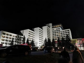 Cars on road by buildings against sky in city at night