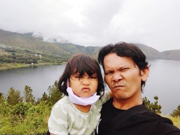 Portrait of smiling young woman standing against lake