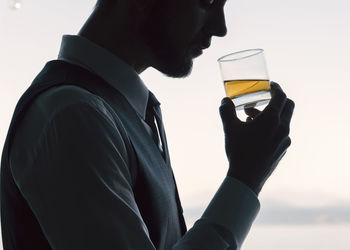 Man holding drink glass against white background