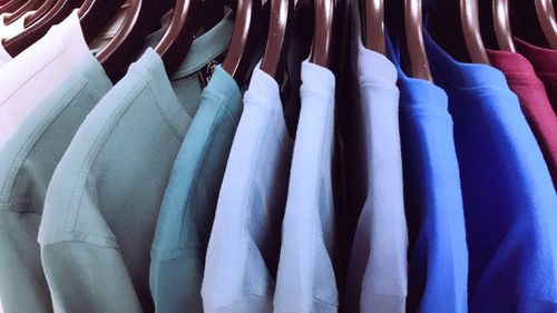 Close-up of multi colored clothes hanging on rack in store