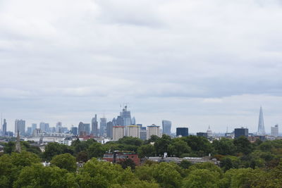 Trees and buildings in city against sky