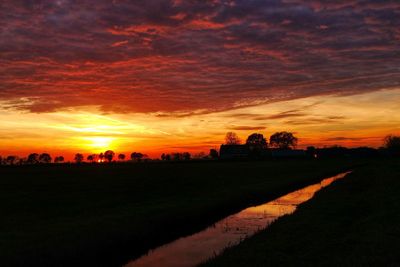 Scenic view of silhouette field against orange sky