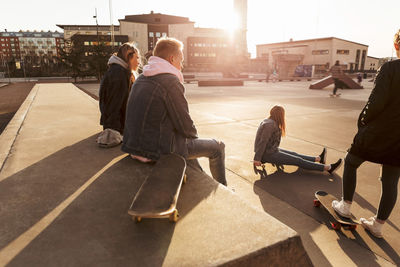 Teenage friends hanging out at skateboard park during sunny day