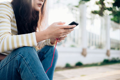 Midsection of woman using mobile phone outdoors