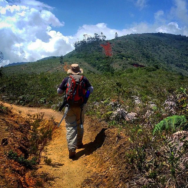 full length, lifestyles, leisure activity, casual clothing, mountain, sky, person, landscape, young adult, cloud - sky, hiking, backpack, standing, nature, tranquil scene, tranquility, mountain range, beauty in nature